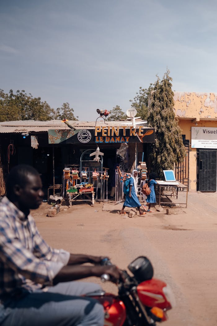 service-04 A vibrant street scene showing a man on a bike, shops, and pedestrians in an African town.